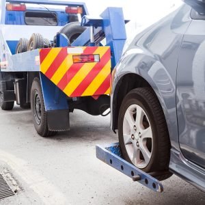 tow truck towing a broken down car on the street