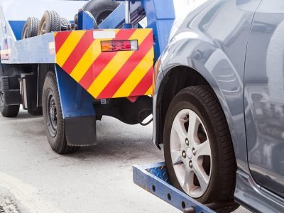 tow truck towing a broken down car on the street